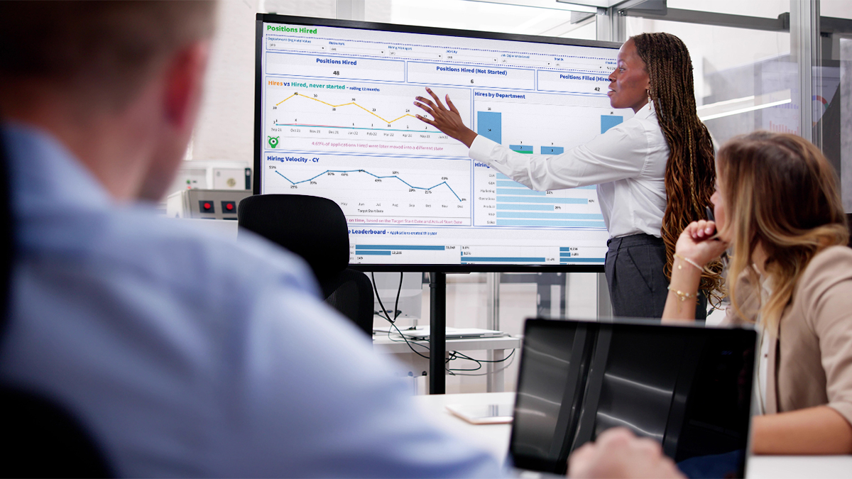 Woman pointing at recruiting dashboard in hiring team meeting