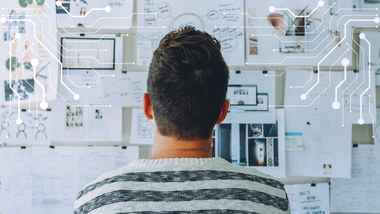 Man looking at wall of recruitment plans on paper considering how to use AI