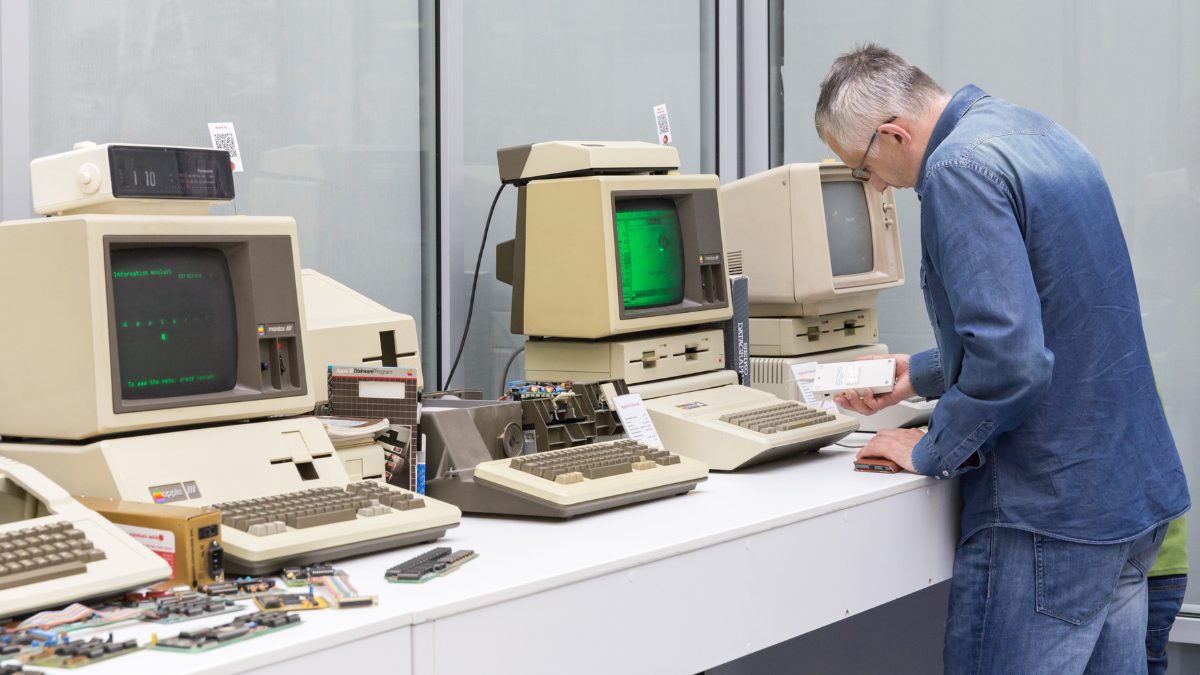 A man works at a computer. The man is wearing a blue lab coat.